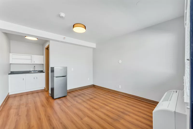 studio apartment with fridge, wood-style flooring, and kitchenette